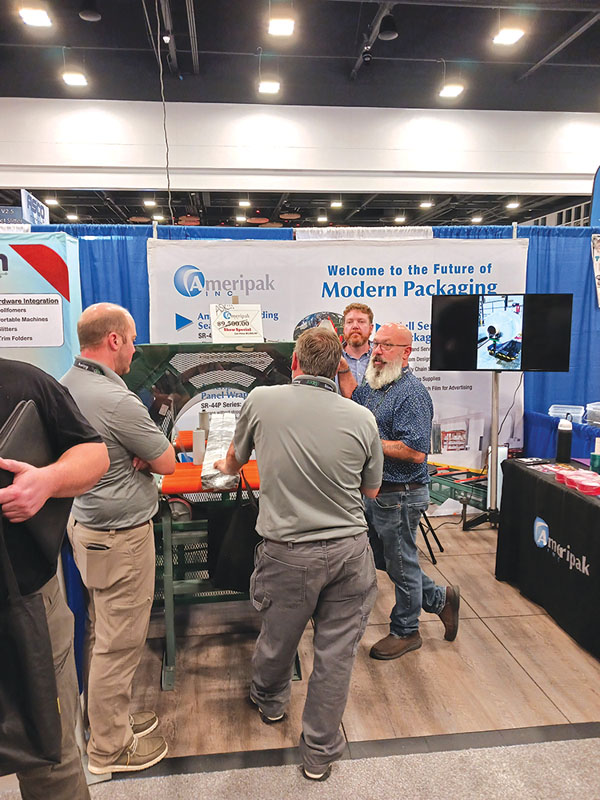 Rob Bowlin (far right) demonstrates the Ameripak packaging machine, which was sold right off the show floor.