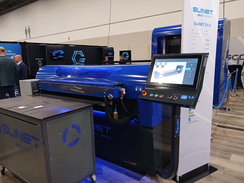 Eddy Pentz (right) demonstrates the Slinet slitter in the ASCO USA, Inc. exhibit. The Slinet S1.5 features integrated coil storage. Note the slit pieces on the table in front of Eddy ... The machine features up to 8 automatically adjustable knives, variable cutting gaps, and bottom-up cross-cutting to prevent scratches. 